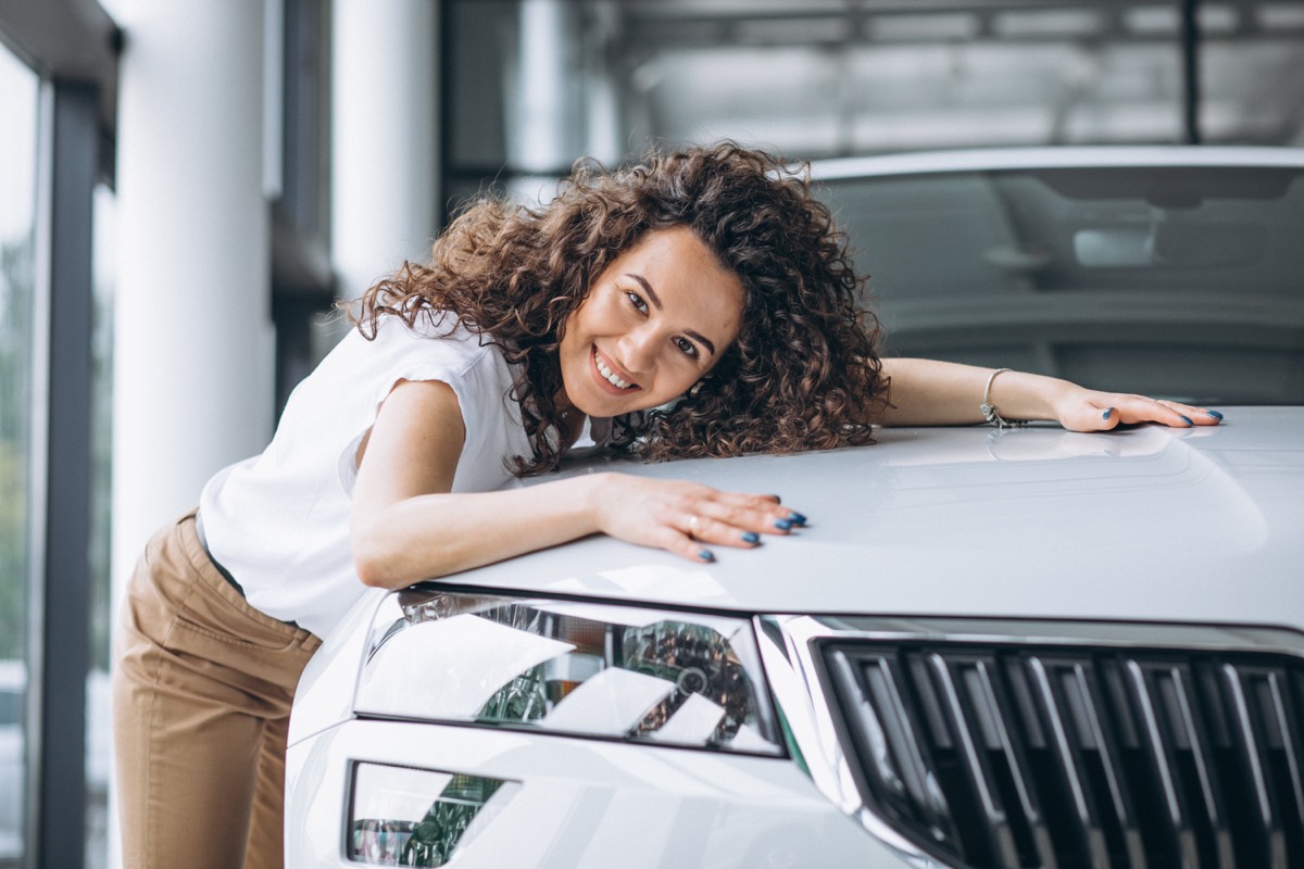 Mulher feliz ao lado do carro recém-segurado