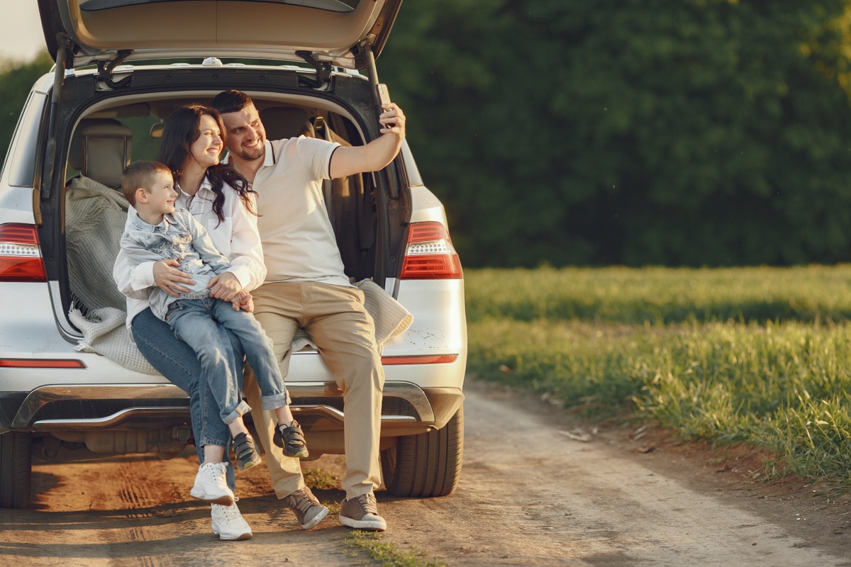 Família feliz ao lado do carro durante um passeio